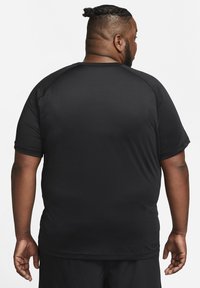 Camiseta atlética negra de manga corta hecha de una tela ligera y transpirable. Presenta un escote redondo y un diseño de hombros sin costuras.