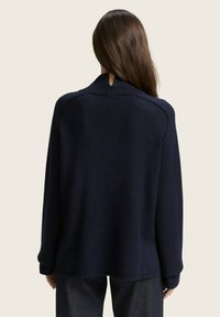 Maglione lavorato a maglia blu navy con colletto alto e polsini a coste, dotato di un'apertura a chiave sulla schiena e una vestibilità morbida.