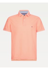 Pikétröja i ljus korall, tillverkad av bomull. Har en randig krage på insidan, två knappar, korta ärmar och en liten logotyp på bröstet.