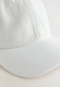 Weißer Baumwoll-Baseballhut mit texturierter Oberfläche, ausgestattet mit einem gebogenen Schirm und gestickten Details am Rand. Beinhaltet einen einzelnen Knopf oben.