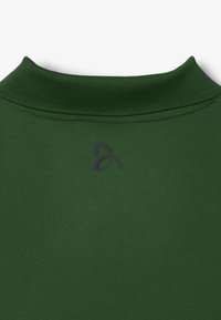 Collare della felpa verde con texture a costine, con un sottile logo nero sul lato sinistro, contro uno sfondo di tessuto liscio.