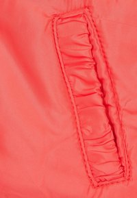 Koraalkleurige stof met een gladde textuur, voorzien van een geraffineerd zakdetail, gestikte randen en een glanzende afwerking op een lichtgewicht materiaal.