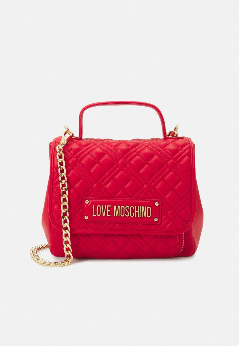 Sac à main matelassé rouge avec une chaîne et une poignée dorées. Dispose d'un plaquette logo dorée et d'une fermeture à rabat. Texture lisse et forme structurée.