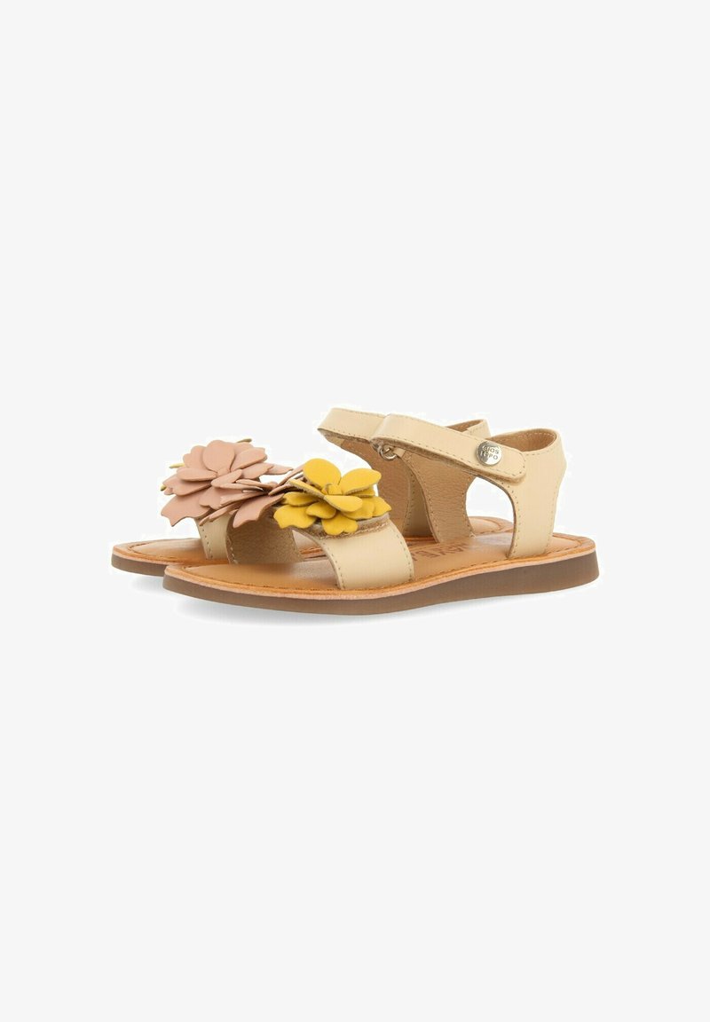 Sandalias beige con acentos florales en rosa y amarillo, con una parte superior de cuero suave, correa ajustable y suela plana.