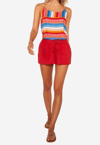 Top sin mangas a rayas coloridas con tirantes finos, combinado con pantalones cortos de lino rojos que presentan un patrón texturizado y cintura con cordón ajustable.