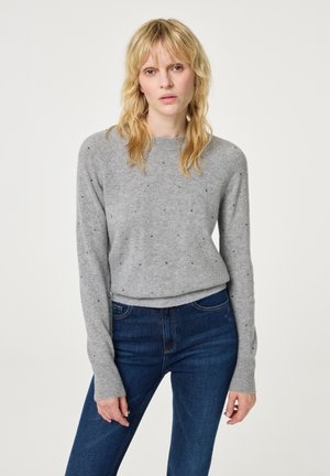 Grijze trui met lange mouwen, voorzien van verspreide kleine versieringen, een ronde halslijn en een ontspannen pasvorm, gecombineerd met donkerblauwe jeans.