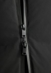 Schwarzer Jackenstoff mit glatter Textur, ausgestattet mit zwei Reißverschlüssen in mattschwarzem Metall und einem schlanken Design entlang der vorderen Öffnung.