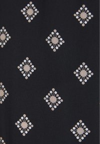 Černá látka s opakujícím se geometrickým vzorem diamantů a kruhových motivů v béžové a bílé barvě. Hladká textura vytvářející dekorativní design.