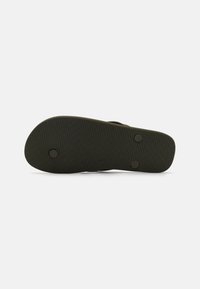 Sort gummisål til sandaler med tekstureret grebsmønster og to runde metalaccenter for stabilitet og holdbarhed. Glat, flad design.