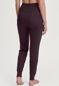 Donk paarse legging met een hoge tailleband, slim design en taps toelopende boorden. Gemaakt van zachte, elastische stof; lijkt glad en lichtgewicht.
