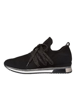 Schwarzer Strick-Sneaker mit dicken strukturierten Schnürsenkeln, weißer und schwarzer Sohle, niedrigem Knöchelkragen und Zuglasche an der Ferse.