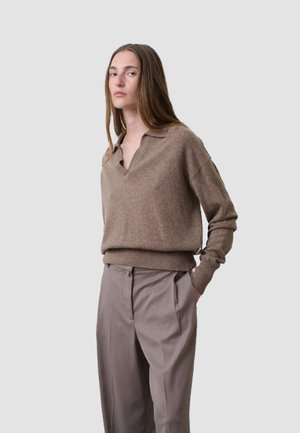 Brown knit sweater with a v-neck and long sleeves, paired with light gray, tailored trousers. Sweater features ribbed hem and cuffs.