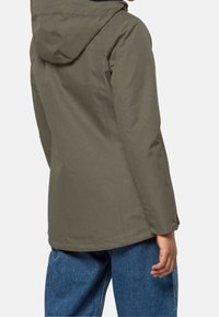 Olivgrön jacka med huva, med en slät yta, skräddarsydd design och synliga sömdetaljer. Huvudtyget verkar lätt och hållbart.