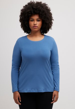 Langarm-Crewneck-Top in Blau, aus weichem Material, mit lockerer Passform und glatter Textur. Flatlock-Nähte, minimale Details.