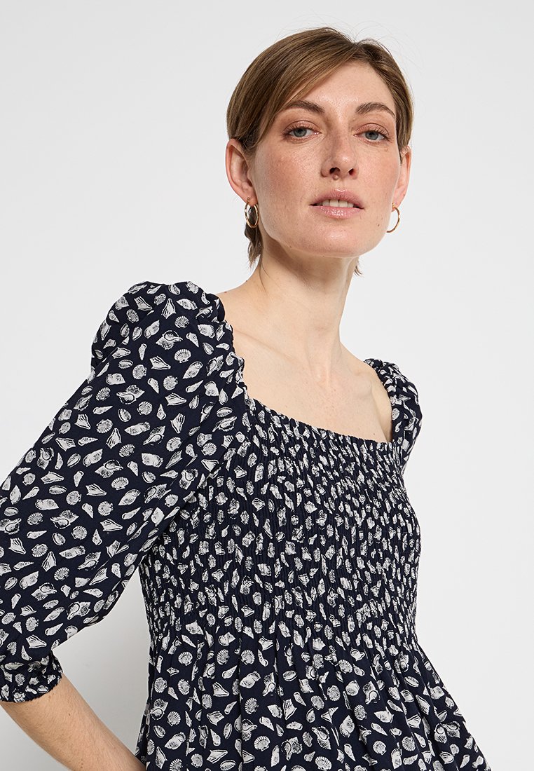 Navyblaues Kleid mit einem gerafften Oberteil, quadratischem Ausschnitt und Puffärmeln. Verfügt über ein weißes Blattmuster auf dem gesamten Stoff.