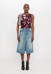 Bodysuit de estampado floral en negro y rojo con un diseño de un solo hombro, combinado con una falda midi de mezclilla azul clara y botas negras hasta el tobillo con acentos metálicos.