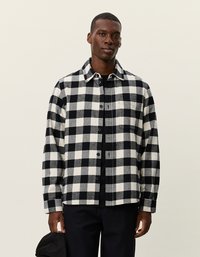 Fekete-fehér kockás ing, flanel anyagból készült; gombos elülső rész, gallér, és egy bal oldali zseb jellemzi.