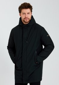 Zwarte geïsoleerde parka met een hoge kraag, ritssluiting aan de voorkant, zijzakken en verstelbare trekkoorden. Glad weefsel.