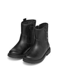 Botas de tobillo negras hechas de cuero suave, con cremallera lateral, punta redondeada y tachuelas decorativas en el lado exterior. Tacón bajo en bloque.