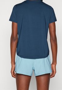 Camiseta atlética de manga corta en azul marino con un corte relajado, combinada con pantalones cortos de un azul claro. Tejido suave con sutiles detalles de costura.