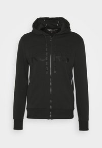 Felpa nera con zip in misto cotone, caratterizzata da un logo frontale con finitura lucida, coulisse e pannelli laterali bianchi a contrasto.