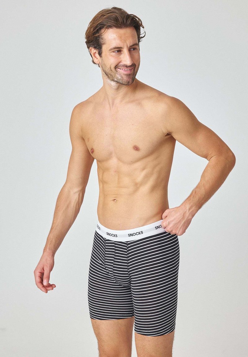 Boxer di lino da uomo a righe bianche e nere con una vita bianca su cui è scritto il nome del marchio "SNOCKS" in caratteri bold; tessuto elastico.