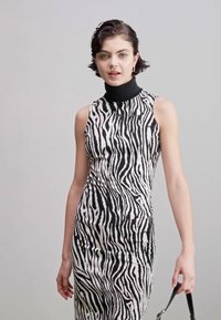 Abito senza maniche con stampa zebra, dotato di collo alto, silhouette aderente e colori a contrasto bianco e nero. Tessuto con una consistenza liscia.