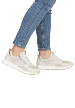 Chaussures de sport en matériaux beige et blanc cassé avec des panneaux en mesh, des accents métalliques et une semelle texturée. Conception à lacets avec une fermeture éclair latérale.