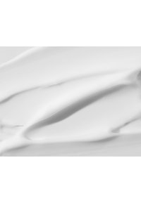 Crème blanche avec une texture lisse et brillante, présentant de légères vagues et arêtes indiquant l'application. Surface douce et réfléchissante sans particules visibles.
