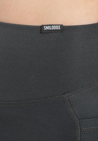 Leggings neri realizzati in un tessuto morbido e stretchy, con una vita brandizzata. Hanno una forma aderente con cuciture sottili e un dettaglio con tasca.