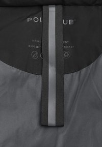 Svart isolerad jacka med en slät yta, en logotagg och ett vertikalt grått band på framsidan med etiketter för miljövänligt material.