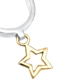 Sølvring med en guldstjerne charm. Stjernen har en hul midte og glatte kanter, der kontrasterer med det polerede sølv.