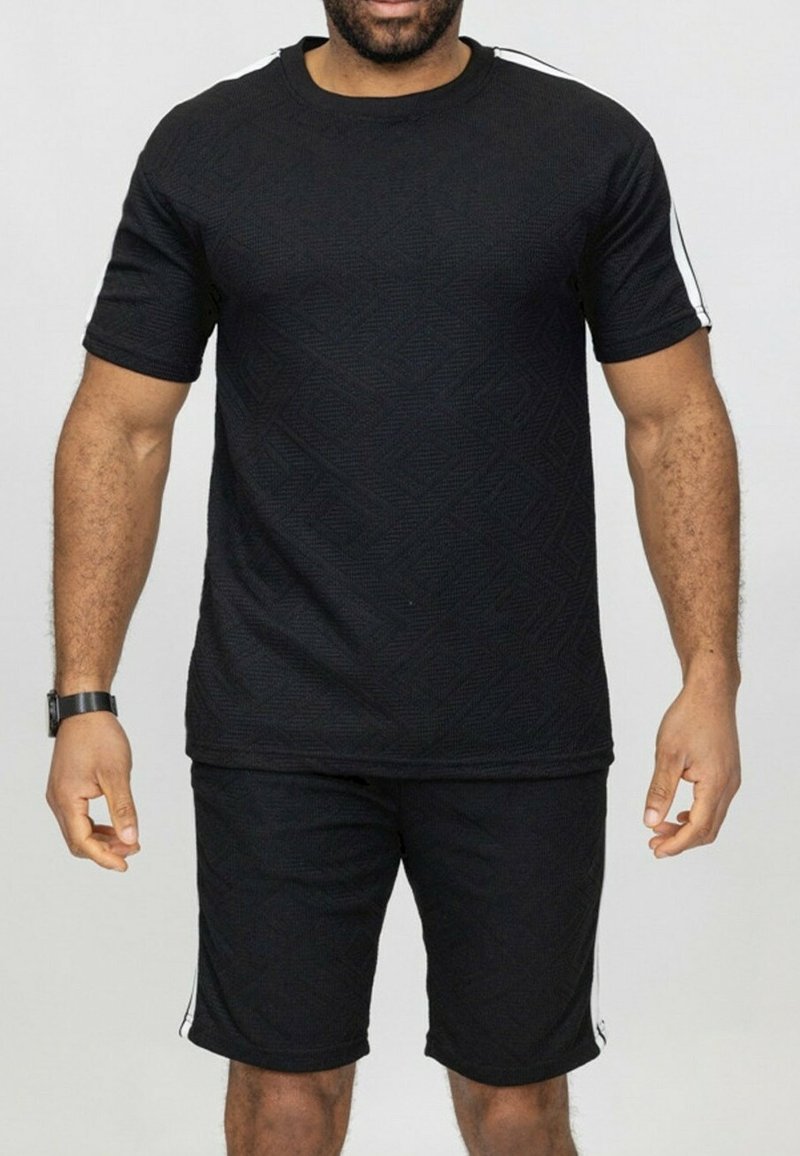 Ensemble de sport noir comprenant un t-shirt à manches courtes texturé et un short assorti. Le t-shirt présente des rayures blanches sur les côtés et un col rond.