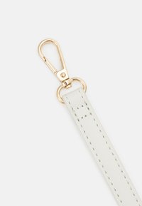 Sangle en faux cuir blanche avec clip en métal doré. La sangle présente des coutures soignées et une texture lisse. Le clip a une forme ovale pour une fixation facile.
