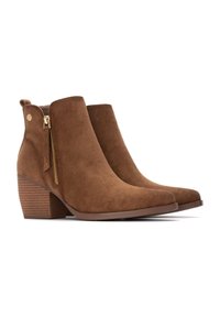 Botas de tobillo de ante marrón con punta afilada, cremallera lateral y tacón apilado, que presentan un diseño texturizado en el tacón.