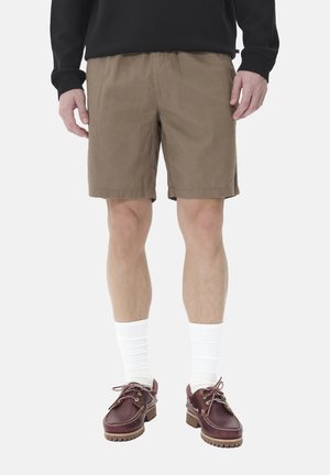 Brown cotton shorts with a relaxed fit, paired with white knee socks and burgundy boat shoes. Simple design, no visible patterns or logos.