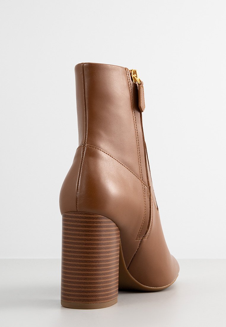 Bottine en cuir brun avec une forme structurée, dotée d'un talon texturé et rayé brun et d'une fermeture éclair sur le côté.