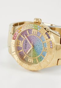 Montre-bracelet en or avec un cadran en dégradé scintillant présentant des teintes roses, violettes, bleues et vertes. Embellie de pierres précieuses multicolores autour de la lunette.
