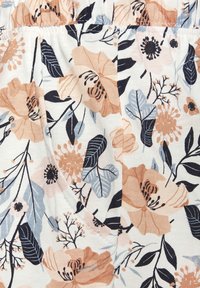 Kvetinová látka s veľkými broskyňovými a modrými kvetmi na bielom pozadí, s detailnými listami a dekoratívnym šitím. Mäkká bavlnená textúra.