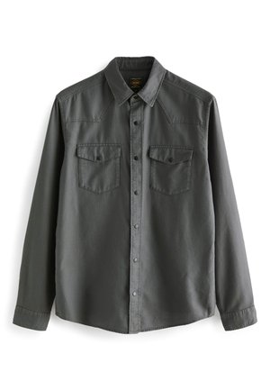 Camicia a maniche lunghe con bottoni in tessuto grigio scuro. Presenta due taschini sul petto, inserti sulle spalle e bottoni a pressione. Texture morbida e liscia.