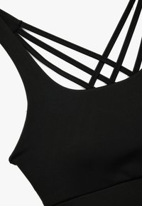 Sort ærmeløs top med en glat tekstur, brede stropper og et geometrisk blonde-design med krydsende stropper bagpå.