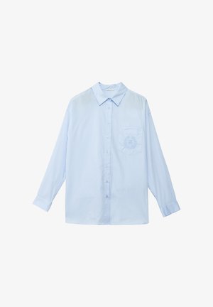 Camicia a maniche lunghe azzurro chiaro con colletto classico, chiusura frontale con bottoni e taschino a sinistra con dettagli ricamati.