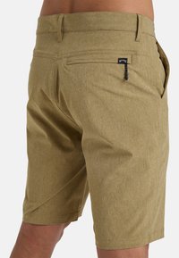 Khaki shorts made of textured fabric, featuring a zippered pocket, back pocket, and a clean, tailored fit.