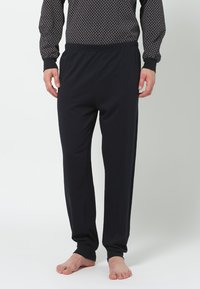 Schwarze Baumwoll-Loungehosen mit einem elastischen Bund, geradem Bein-Design und weicher Textur, kombiniert mit einem gemusterten Langarmoberteil.