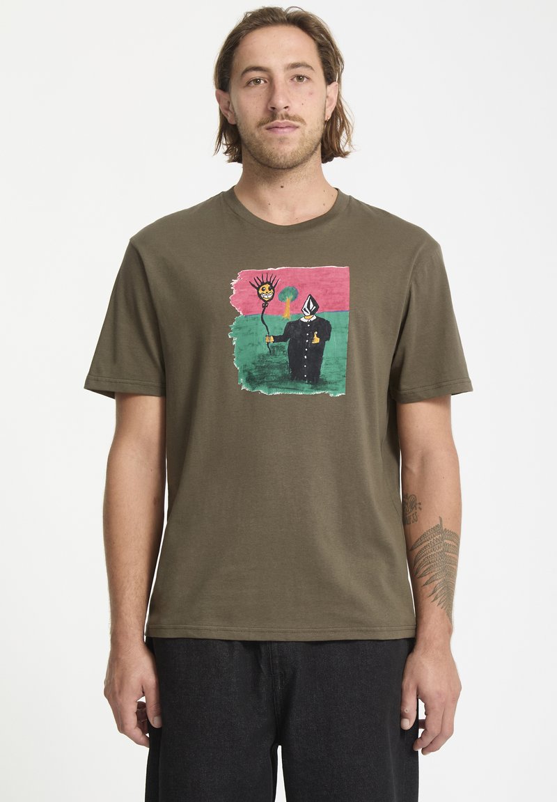 T-shirt en coton vert olive avec un design graphique coloré représentant un soleil souriant et une silhouette en manteau noir. Manches courtes, coupe décontractée.