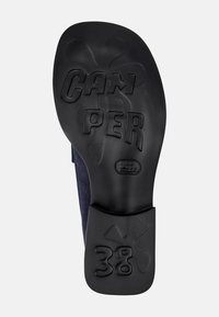 Μαύρη καουτσούκ σόλα παπουτσιού με ανάγλυφη τη λέξη "CAM PER" και το μέγεθος "38". Διαθέτει ομαλή υφή και διακοσμητικό λουλουδάτο σχέδιο στη φτέρνα.