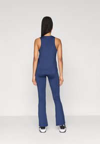 Mørkeblå ermeløs topp og matchende skjørtleggings, begge laget av et mykt og glattt stoff. Antrekket er tettsittende med minimal detaljer.