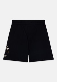 Pantalones cortos de algodón negros con una cinturilla elástica, que presentan un gran diseño de logo color crema en la pierna izquierda. Textura suave, corte a la altura de la rodilla.