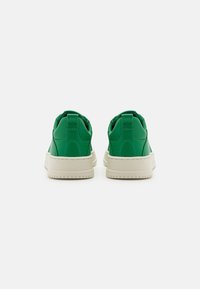 Gröna syntetiska sneakers med rund tå och dämpning, med en vit gummisula och sydda detaljer på hälområdet.