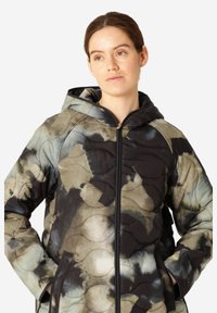 Chaqueta acolchada con capucha en tonos apagados de negro, verde y beige con patrones abstractos, que cuenta con un cierre delantero y bolsillos laterales.
